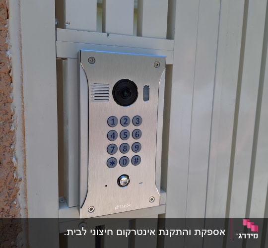 אינטרקום עם מצלמה ולוח מקשים על שער מתכת